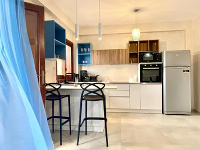 a kitchen with blue cabinets and a refrigerator and stools at Casa Perla Marina sul mare in Castellammare del Golfo
