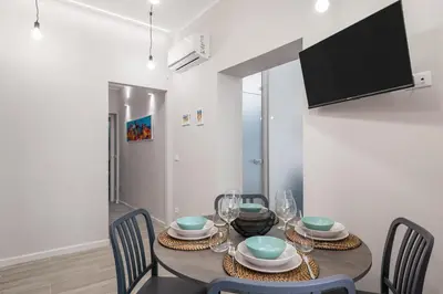a dining room with a table with chairs and a tv at LE PORTE DEL KASSARO in Palermo