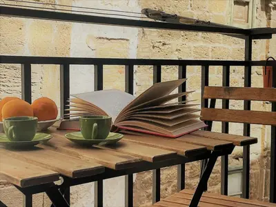 a wooden table with books and cups and oranges on it at Shallah Apartment nel cuore del centro storico di Palermo in Palermo