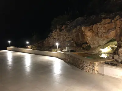 a swimming pool at night with a rock wall at Villa MiraScopello in Castellammare del Golfo