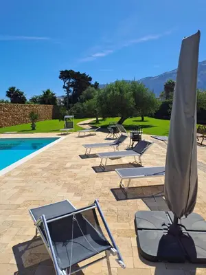a group of lounge chairs and an umbrella next to a pool at Villa Albamonte in Carini