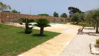 a park with benches and palm trees and a pool at Villa Albamonte in Carini