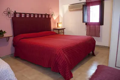 a bedroom with a red bed with a red blanket at Bed And Breakfast Maria in Scopello