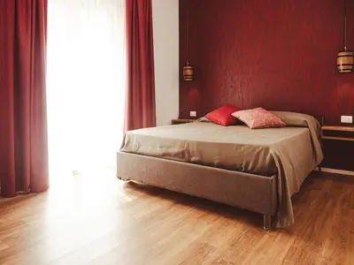 a bedroom with a bed with red walls and wooden floors at U Zuccareddu in Alcamo