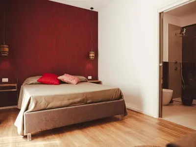 a bedroom with a bed with a red wall at U Zuccareddu in Alcamo