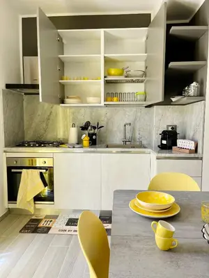 a kitchen with white cabinets and a table with yellow chairs at La Terrazza del Capo in San Vito lo Capo
