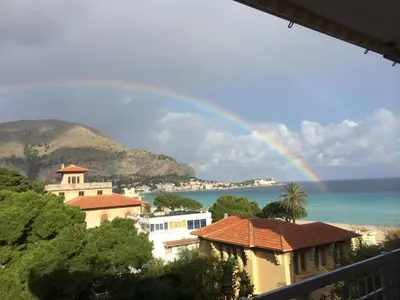 a rainbow over a city with houses and the ocean at Mondello Luxury Apartment on the Beach in Mondello