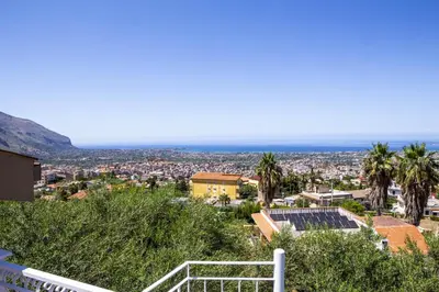 a view of a city with palm trees and the ocean at La Murgiulina in Carini