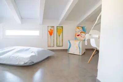 a bedroom with a bed and paintings on the wall at Villa Majestatis in Scopello