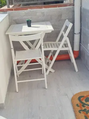 a white table and a chair sitting next to a table and a stool at Casetta Bella Nonna Rosetta in Mondello