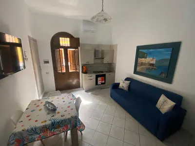 a living room with a blue couch and a table at La casetta del sole in Castellammare del Golfo