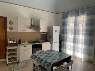 a kitchen with a table and a stove and a refrigerator at Casa Vacanza Sicilia Dolce Mare in Balestrate