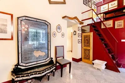 a living room with a red staircase and a chair at La Dimora del Conte, immersa nel verde in centro città in Palermo