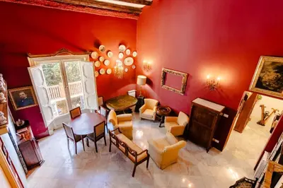 a living room with red walls and a table and chairs at La Dimora del Conte, immersa nel verde in centro città in Palermo