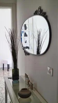 a mirror on a wall with a vase on a table at Àrima Mondello Apartment in Mondello