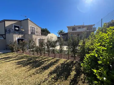 a fence with trees in front of a house at Villa Simo in Altavilla Milicia