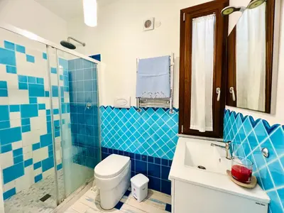 a blue tiled bathroom with a toilet and a shower at Rosa di Mare in Capaci