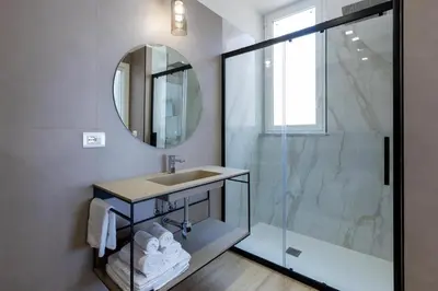 a bathroom with a sink and a shower with a mirror at Le Gemme di Cavour Luxury Rooms in Palermo