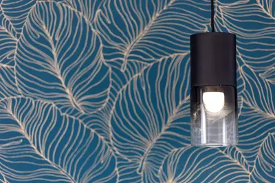 a lamp hanging from a wall with a leafy wallpaper at Le Gemme di Cavour Luxury Rooms in Palermo
