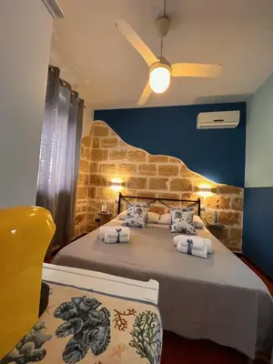 a bedroom with a bed and a ceiling fan at Celeste Rooms in San Vito lo Capo