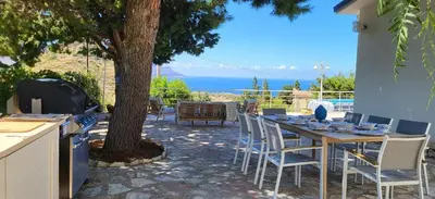 a table and chairs with a view of the ocean at Villa Ballerina Bianca in Scopello
