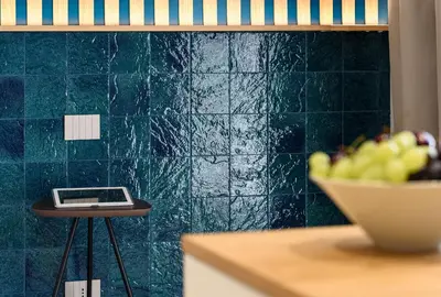 a scale on a stool next to a green tiled wall at IL MARE DENTRO SUITES in San Vito lo Capo