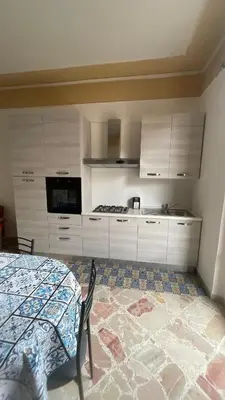 a kitchen with white cabinets and a table with a rug at APPARTAMENTO MAESTRALE in Balestrate