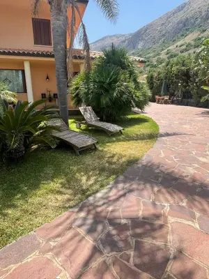 two wooden benches sitting in the grass near a house at Martanna Rooms in Carini