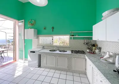 a kitchen with green walls and white counter tops at Solemar Sicilia - Villa Elis in Bagheria