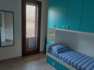 a bedroom with a bed and blue cabinets and a mirror at Casa Vacanze Villa Pomelia in Campofelice di Roccella