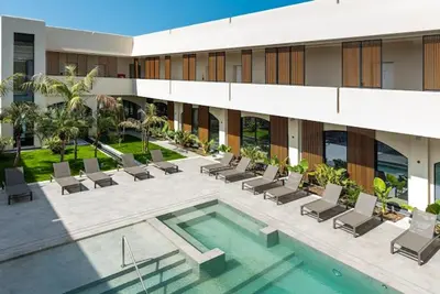 a hotel with a swimming pool and chairs and a building at Casa Vacanze Villa Pomelia in Campofelice di Roccella