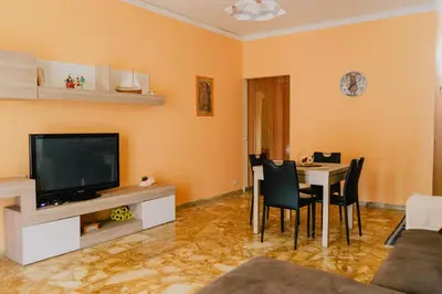 a living room with a television and a table with chairs at Casa Vacanza Stella Maris in Isola delle Femmine