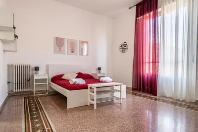 a white bedroom with a red bed and a table at [La Maiolica] - Centro storico in Palermo