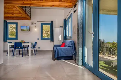 a living room with a table and a blue chair at Villa Holidays Vista Torre Bennistra in Scopello in Scopello