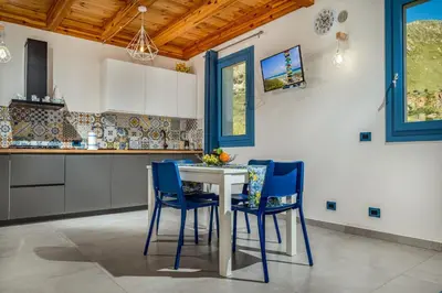 a kitchen with a white table and blue chairs at Villa Holidays Vista Torre Bennistra in Scopello in Scopello