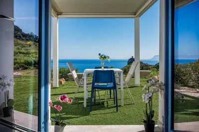 a table and chairs on a patio with a view of the ocean at Villa Holidays Vista Torre Bennistra in Scopello in Scopello
