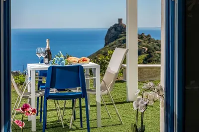a table with two chairs and a table with wine glasses at Villa Holidays Vista Torre Bennistra in Scopello in Scopello
