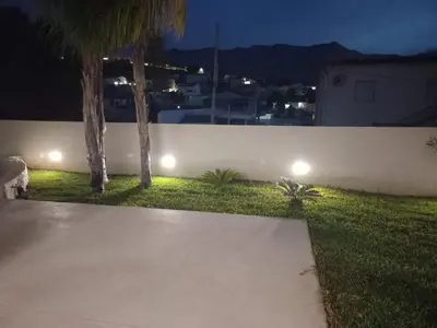 a garden with palm trees and a fence at night at Casa vacanze I colori del mare in Alcamo Marina