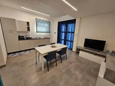 a living room with a table and chairs and a kitchen at Casa vacanze I colori del mare in Alcamo Marina