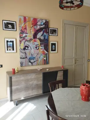a dining room with a large painting on the wall at La casa di Nanà in centro in Palermo