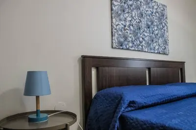 a bedroom with a blue bed and a table with a lamp at Alexander House in Palermo
