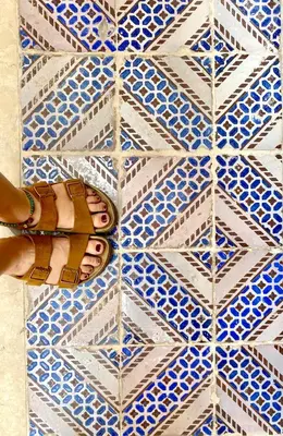 a woman with her foot on a blue and white tiled floor at Casa 900 in Castellammare del Golfo