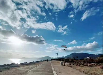 a road next to a beach with a cloudy sky at Ally's house in Palermo