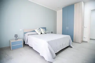 a white bedroom with a bed and a night stand at La Chiostrina in Castellammare del Golfo