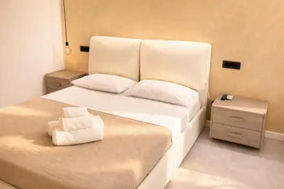 a bedroom with a bed with white sheets and towels at Giardino Lussemburgo, Elegante e confortevole appartamento tra Mondello e il centro storico di Palermo in Palermo