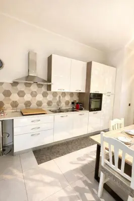 a kitchen with white cabinets and a table in it at Giardino Lussemburgo, Elegante e confortevole appartamento tra Mondello e il centro storico di Palermo in Palermo