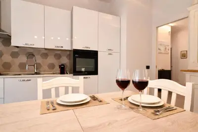 a kitchen with a table with two glasses of wine at Giardino Lussemburgo, Elegante e confortevole appartamento tra Mondello e il centro storico di Palermo in Palermo