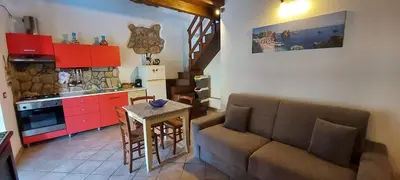 a kitchen and a living room with a couch and a table at Al ficodindia in Scopello