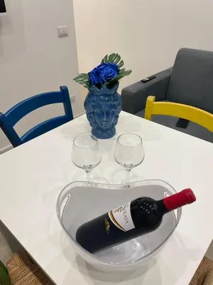 a bottle of wine in a bowl on a table with two glasses at Casa vacanze Soraja in Palermo