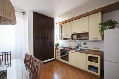 a kitchen with white cabinets and a table with a dining room at Casa Sul Mare Seaside apt in front of the sea in Palermo
